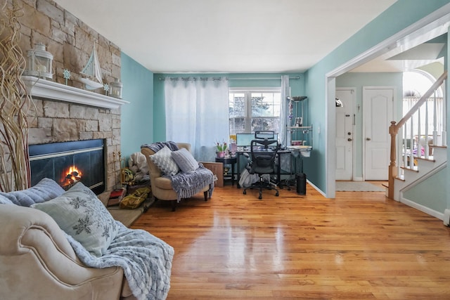 sitting room featuring a fireplace, stairway, baseboards, and wood finished floors