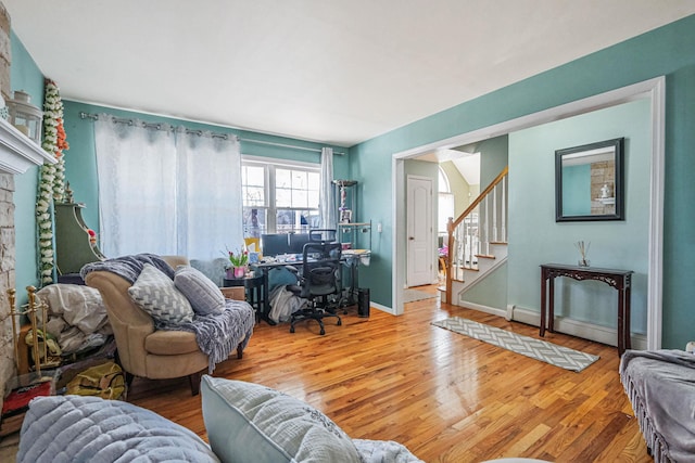 living room featuring a baseboard heating unit, stairs, baseboards, and wood finished floors