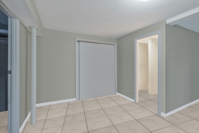 unfurnished bedroom with light tile patterned floors, a closet, and baseboards