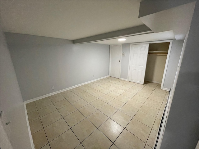 unfurnished bedroom with a closet, light tile patterned flooring, and baseboards