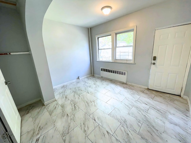 foyer featuring marble finish floor, baseboards, and radiator heating unit