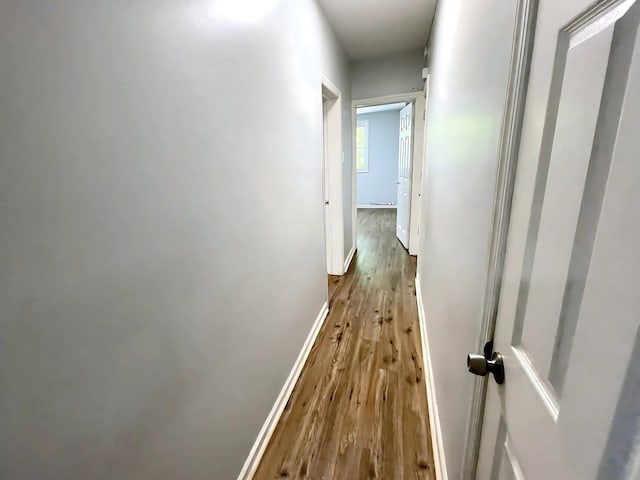 hallway featuring baseboards and wood finished floors