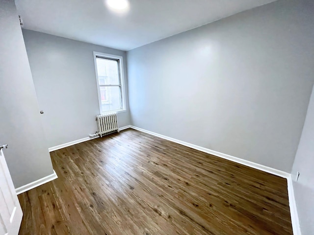 spare room featuring radiator heating unit, wood finished floors, and baseboards