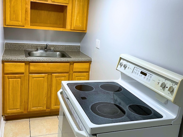 kitchen featuring dark countertops, light tile patterned floors, white range with electric stovetop, and a sink