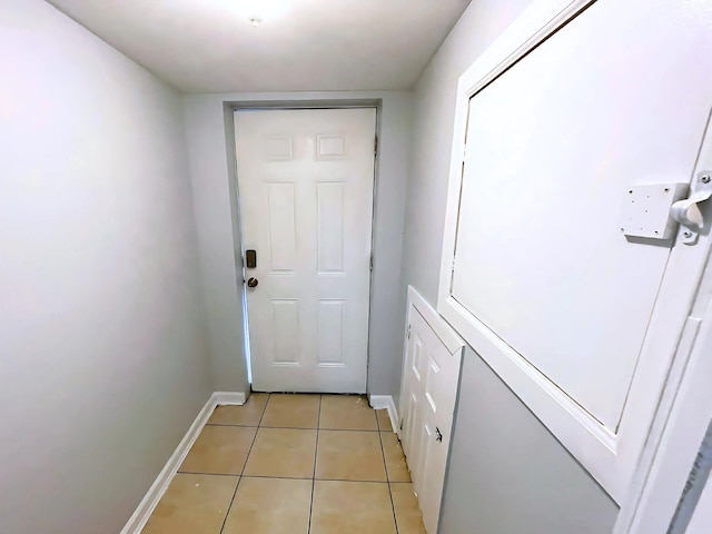 doorway with light tile patterned floors and baseboards