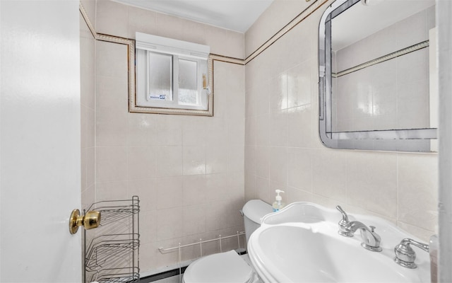 bathroom featuring a sink, tile walls, and toilet