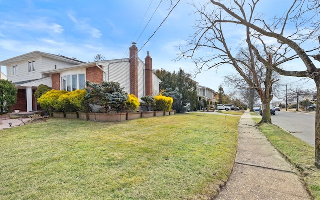 view of home's exterior with a yard, brick siding, and a chimney