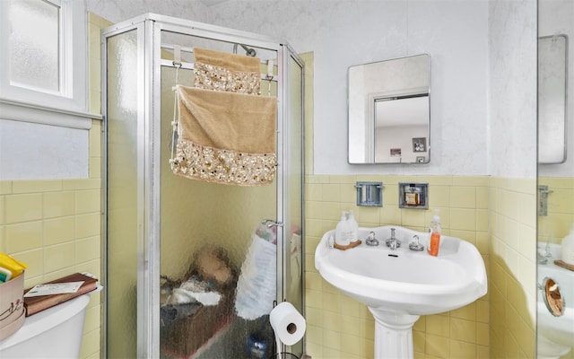 full bath with wainscoting, toilet, tile walls, and a shower stall