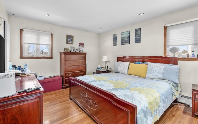 bedroom featuring a baseboard heating unit, multiple windows, light wood-style flooring, and recessed lighting