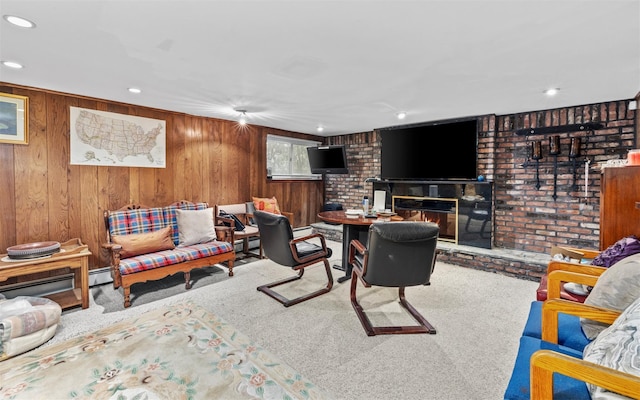 living area featuring wood walls, a fireplace, a baseboard heating unit, and carpet flooring