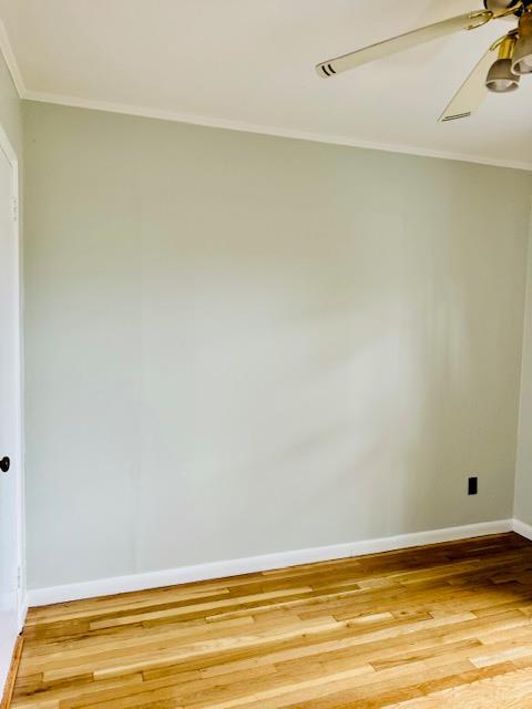 spare room with ornamental molding, ceiling fan, light wood finished floors, and baseboards