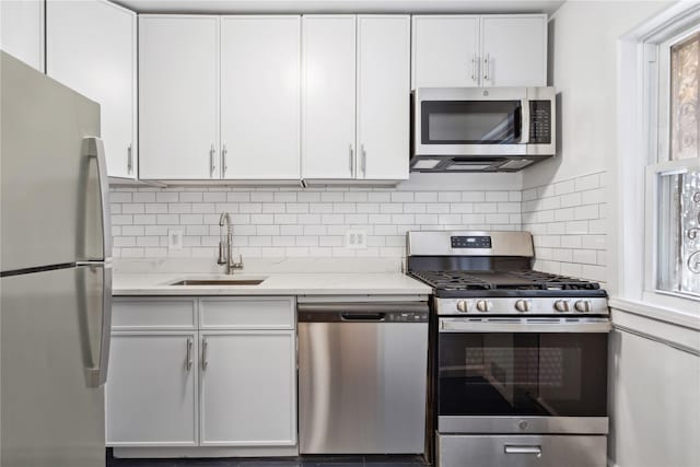 kitchen featuring appliances with stainless steel finishes, white cabinetry, and a sink