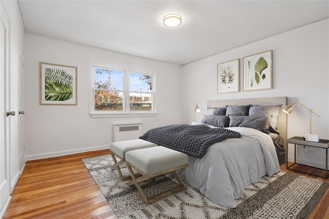 bedroom featuring light wood-style floors, radiator heating unit, and baseboards