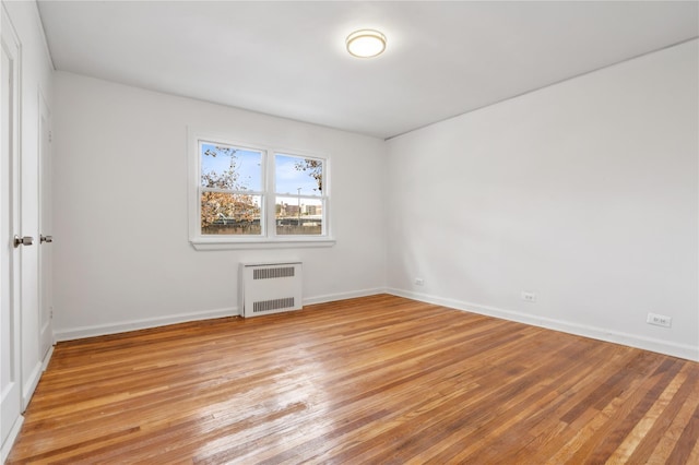 empty room featuring baseboards, light wood finished floors, and radiator