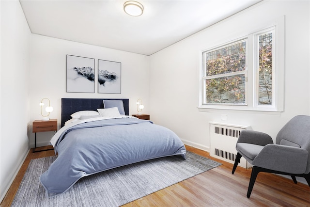 bedroom featuring radiator heating unit, wood finished floors, and baseboards