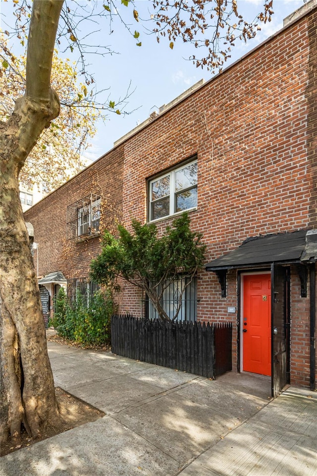 view of front of home featuring brick siding and fence