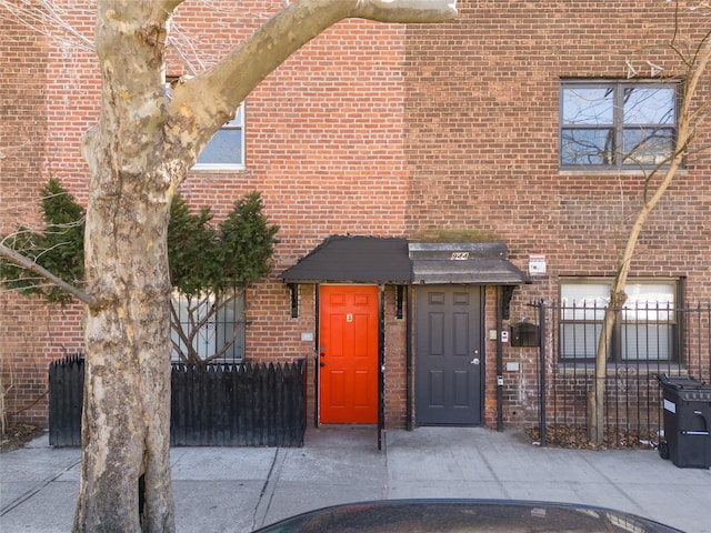 view of front of house featuring brick siding and fence