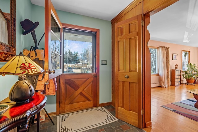 interior space with baseboard heating, wood finished floors, and baseboards