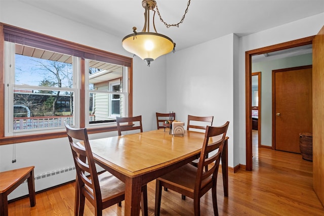 dining room with a baseboard radiator, baseboards, and light wood-style flooring