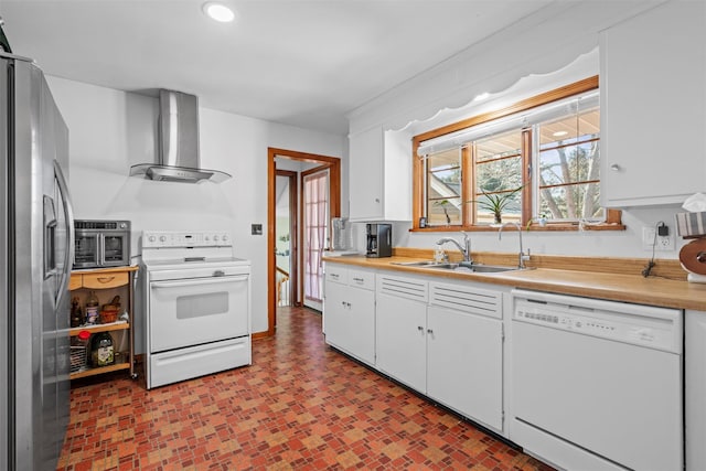 kitchen featuring white appliances, a sink, white cabinets, light countertops, and wall chimney range hood