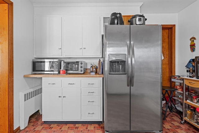 kitchen with stainless steel appliances, radiator, light countertops, and white cabinets