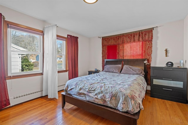 bedroom with a baseboard radiator and light wood-style flooring