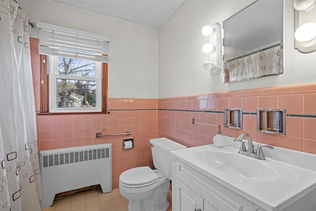 full bathroom featuring toilet, a wainscoted wall, vanity, tile patterned floors, and radiator heating unit