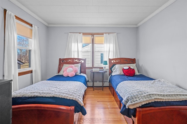 bedroom with light wood-style floors, a baseboard radiator, and crown molding