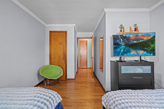 bedroom with baseboards, wood finished floors, and ornamental molding