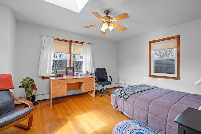 bedroom featuring ceiling fan, a baseboard radiator, a skylight, and light wood-style flooring