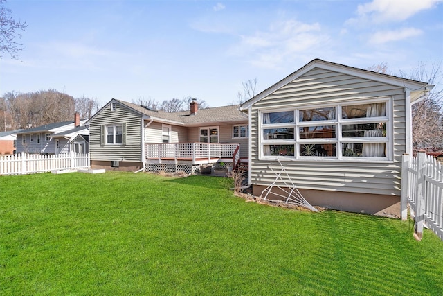 rear view of property featuring a chimney, fence, a deck, and a yard