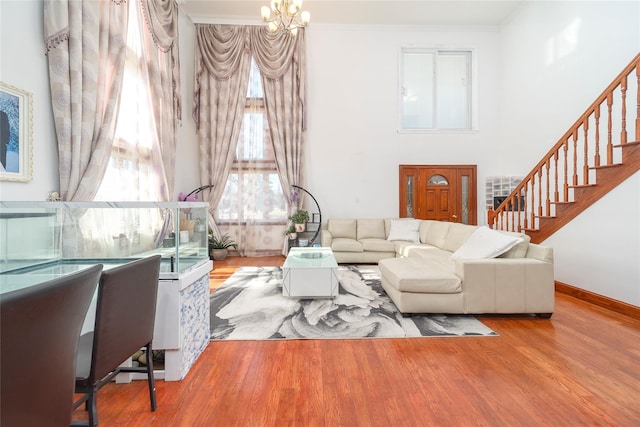 living area with a notable chandelier, a high ceiling, ornamental molding, wood finished floors, and stairs