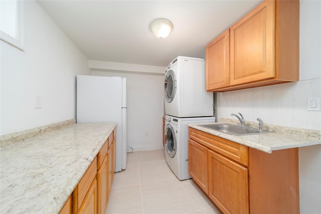 laundry area featuring a sink, cabinet space, stacked washer / dryer, and light tile patterned flooring