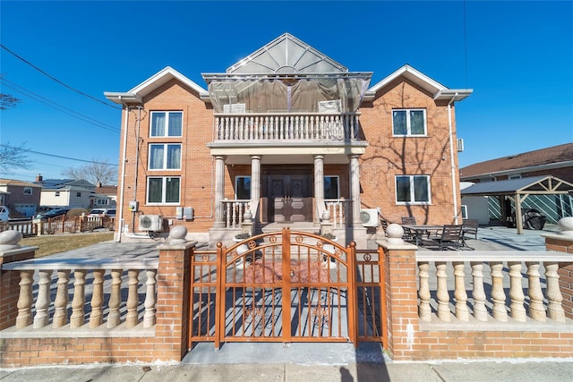 view of front of home with a fenced front yard, a balcony, brick siding, french doors, and a gate