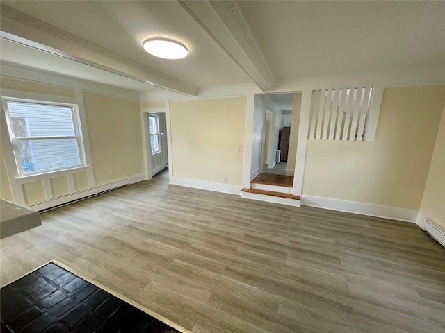 spare room with a baseboard radiator, wood finished floors, baseboards, beam ceiling, and crown molding