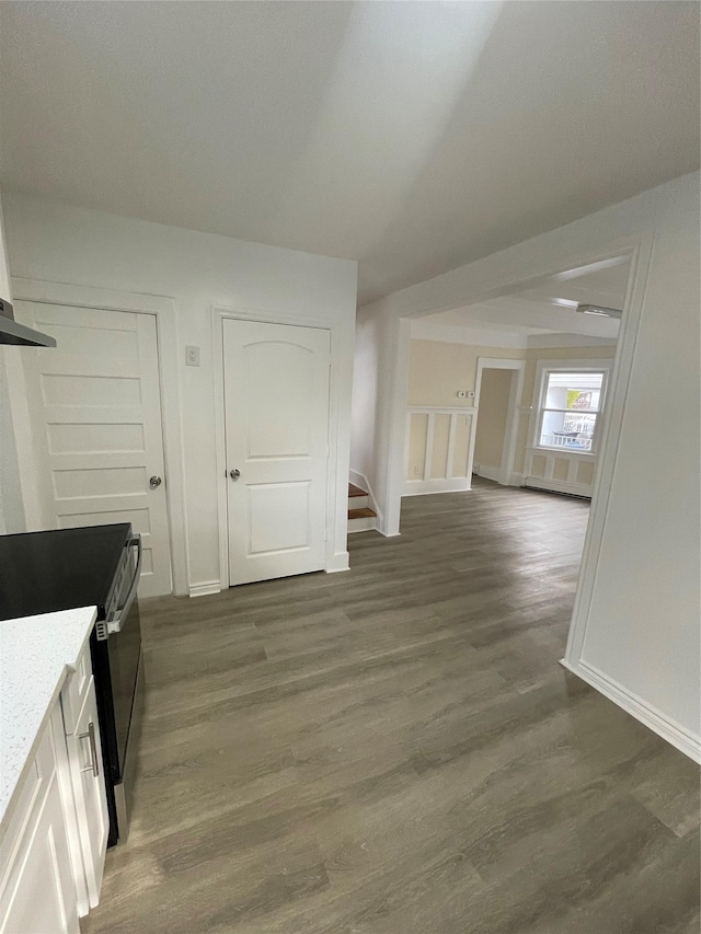 interior space with baseboards, wood finished floors, light stone countertops, and black electric range oven