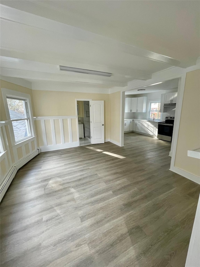 spare room featuring a sink, wood finished floors, and baseboards