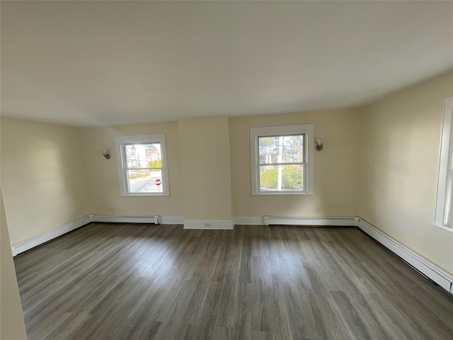 empty room with dark wood-style floors, plenty of natural light, and baseboard heating