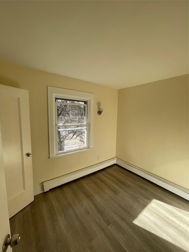 empty room featuring dark wood-type flooring and baseboard heating