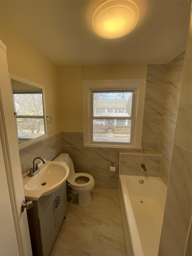 full bathroom with a garden tub, toilet, vanity, tile walls, and marble finish floor