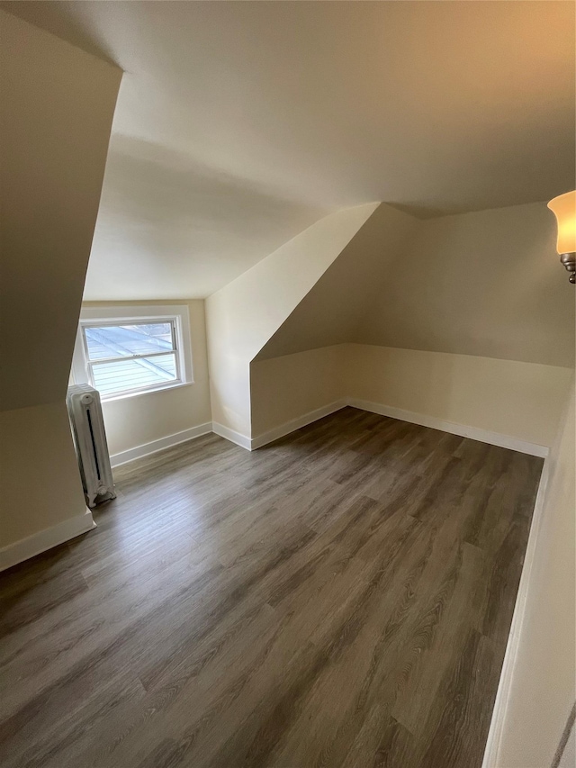 bonus room with radiator, baseboards, vaulted ceiling, and dark wood-type flooring