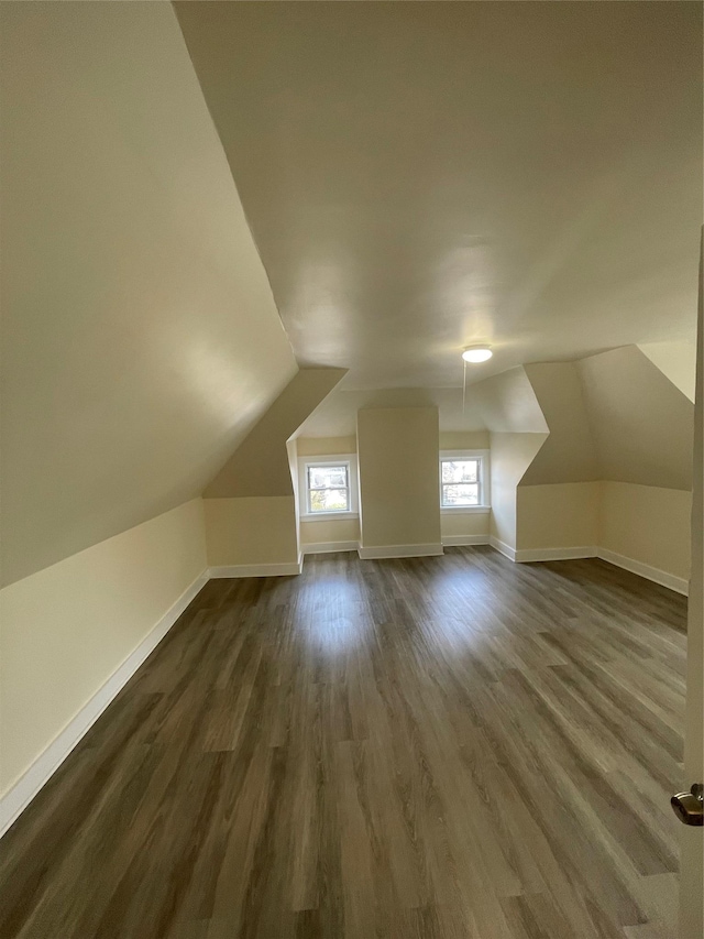 bonus room with dark wood-type flooring, lofted ceiling, and baseboards