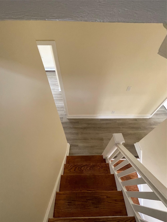 stairway with baseboards and wood finished floors