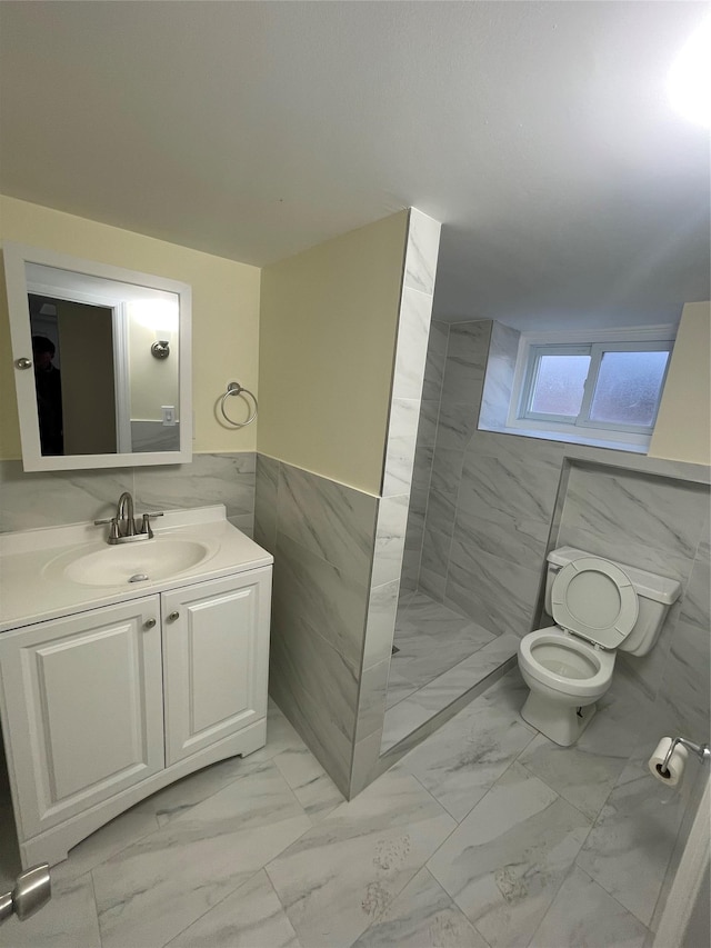 bathroom with tiled shower, toilet, a wainscoted wall, marble finish floor, and tile walls