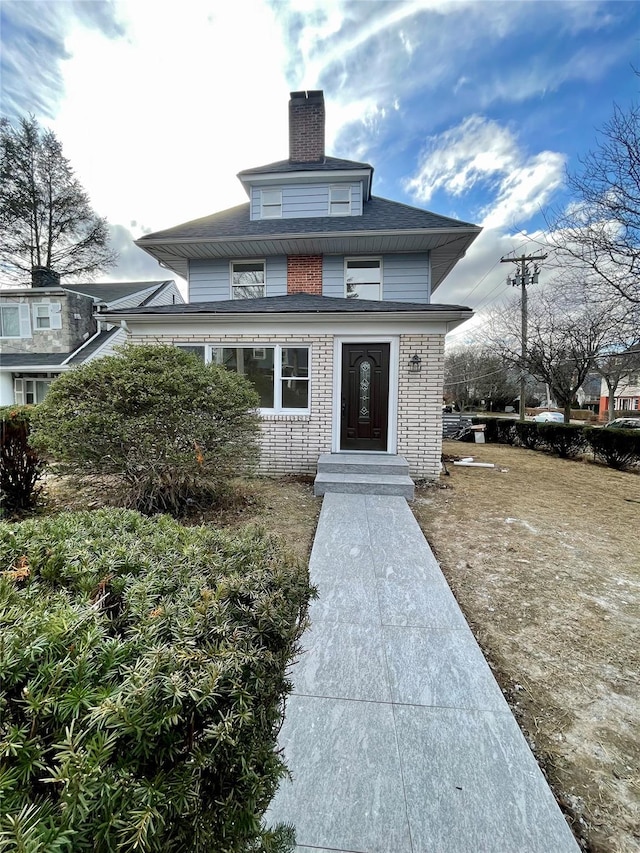 view of exterior entry with a chimney and brick siding