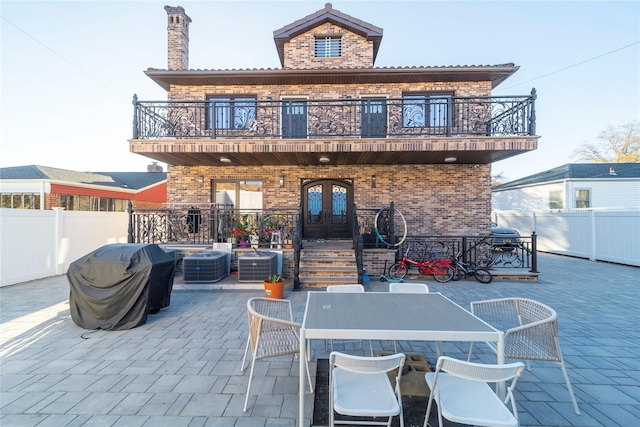 rear view of property with french doors, a fenced backyard, a patio, and a balcony