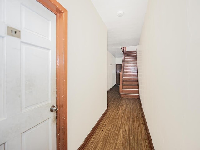 hallway with dark wood-style floors, stairway, and baseboards