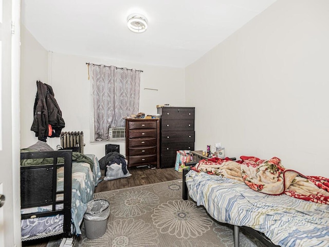 bedroom with radiator heating unit and wood finished floors