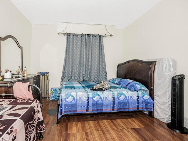 bedroom featuring radiator heating unit and wood finished floors