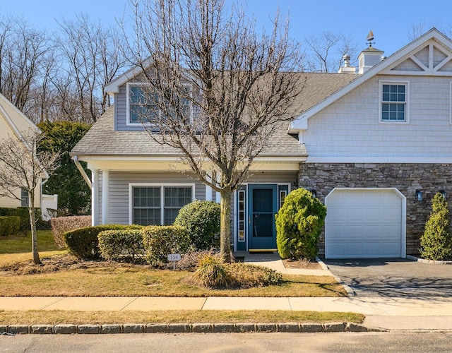 view of front of house featuring a garage, concrete driveway, roof with shingles, and stone siding